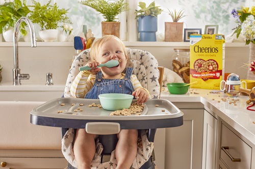 Young child in high chair eating a bowl of Cheerios